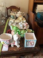 Full view of the children's tea set and accompanying ceramic figurines displayed on a wooden surface, showing various bone china pieces and decorative items.