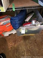 Photo of blue camping tent bag, two orange Fram air filter boxes, and a plastic bin with camping supplies including air horn and multi-tool.