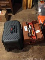 Rubbermaid step stool/tool box next to a brown fishing tackle box with open compartments showing fishing lures inside