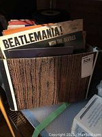 Photo of cardboard box filled with various vinyl albums, including visible Beatles album titled 'Beatlemania!'