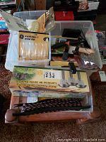 Clear view of plastic bins with various BBQ tools, GE light bulbs in packaging, and a box of solar powered garden lights.