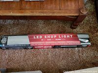 Photo of boxed 4ft aluminum LED shoplight with product details visible on box.