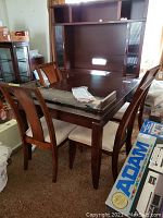 Dining table with four chairs arranged around it in a room with other furniture and items.