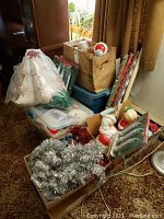 Overview of boxes and totes containing Christmas decorations, including wrapping paper, tinsel, and ornaments.