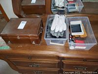Wooden jewelry box, men's clutch, wallets, gloves and shoe care items arranged on a wooden desk