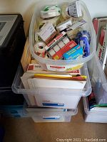 Overview photo showing three plastic storage bins filled with tape products and file folders, arranged stacked on top of each other.