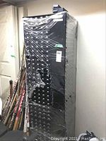 Full-height view of black metal rotating storage carousel wrapped in plastic