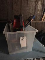 Photo of translucent plastic bin containing three work lights inside against a dark wooden paneled background.