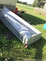 View of aluminum boat upside down on grass showing full-length hull bottom with three keel ribs and riveted seams