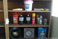 Wooden shelves holding multiple chemical and cleaner bottles, two speaker systems visible at bottom shelf including US Acoustics Krank 12" diameter speaker and Roadmaster 2-way model RTS2000TM speaker.