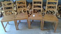 Front view of four Ikea Jokkmokk solid wood ladder back dining chairs arranged in a row showing seats and backs with some visible scratches.