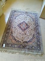 Full view of the rectangular area rug showing traditional medallion and floral pattern design with beige, cream and blue colors.