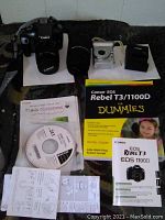 Overview of all items: DSLR with lens, telephoto lens, compact camera, charger, manuals and CD