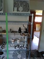 Shelving unit with multiple home decor and kitchen items including antler-themed accessories, bottle openers, mugs and two wall clocks.