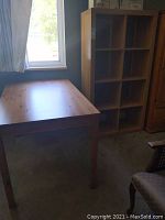 Photo showing the rectangular solid wood dining table next to the cube shelving unit near a window.