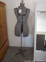 Full front view of gray dress form on metal stand