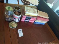 Two jars filled with pennies and a stack of hardcover books including three Winston Churchill volumes on a wooden table.