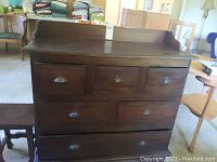 Front view of dark chocolate wooden dresser with backsplash, showing all six drawers and vintage metal seashell handles.