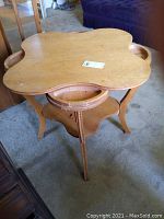 Full view of golden oak antique card table with unique cloverleaf top, showing overall shape, leg decor, and middle shelf.