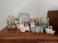 Overview of lot items on wooden surface including vases, ceramic animals, religious pictures and rosary beads