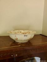 Front side view of vintage ceramic bowl on wooden surface showing floral pattern and wide diameter.