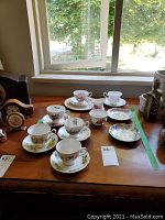 Wide view of all cups and saucers on a wooden table, showcasing varied floral patterns.