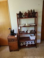 Front view showing wood bookcase with shelves containing various decorative items alongside wooden end table with drawer and brass knob.