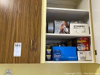 Shelves with various light bulb boxes including Noma, Stanpro, halogen bulbs, Swan box, and parts of packing boxes.