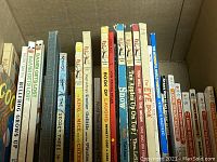 Box of various children's books tightly packed showing spines with titles such as Bambi Gets Lost, Bullfrog Grows Up, King of Mice, Doctor Dolittle, and others.