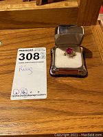 Two rings displayed next to branded lot card and ring box