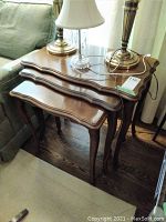 Set of three nested wooden tables showing top surfaces and legs beside couch.