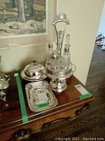 Overview of cruet set on stand between round lidded dish and rectangular tray