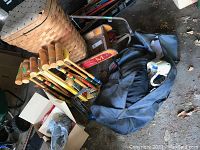 Photo showing wood croquet set with wooden mallets and wickets, a woven basket, hockey equipment bag with white helmet, and some sticks.
