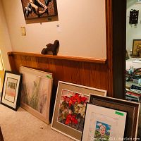 Several framed artworks and a small wood carving displayed on shelf and floor