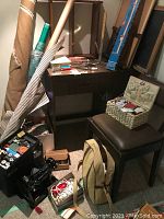 Desktop area showing fabric bolts, sewing supplies in toolbox and basket, storage chair