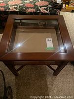 Top view of closed wood and glass display table showing glass inset top and wooden frame.