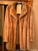 Front view of light beige mink coat on hanger, showing overall appearance.