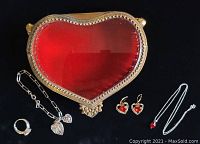 Photo showing all items including heart-shaped jewellery box with red glass lid, sterling silver ring with cubic zirconia, bracelet, necklace with red heart pendant, and Napier earrings.