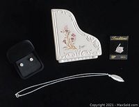 Photo of beige porcelain piano trinket box, sterling silver leaf necklace, stud earrings in black velvet box, and ring with display card