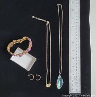 All four jewelry pieces: purple faceted stone stretch bracelet, two sterling silver necklaces including a pendant crystal necklace, and a pair of sterling silver earrings with purple crystals shown next to ruler for size reference