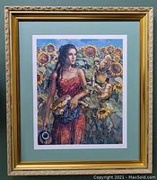 Framed and matted color lithographic print showing a woman in red dress holding a basket, standing among sunflower plants