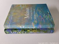 Two large hardcover art books lying flat stacked, showing front cover artwork and titles related to Claude Monet.