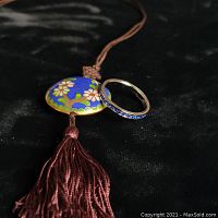 Photo showing cloisonne pendant and sterling silver eternity ring with blue stones on a black background, highlighting colors and details.
