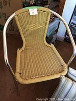 Close-up of one metal frame chair with woven rattan seat and backrest.