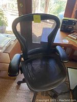 Front view of black mesh high-back office chair on caster base
