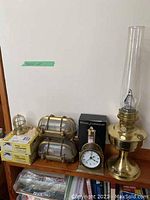 View of lot items including oil lamp, clock, storm glass, and bulkhead lights
