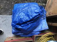 Blue tarp folded with metal grommets visible at edges, placed next to boxes