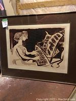 Framed print depicting a seated lady playing a grand piano in sepia tones