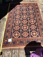 Full view of navy blue geometric area rug on wooden floor with measuring tape along one edge