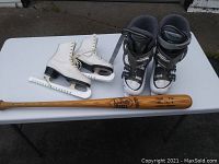 Photo shows white size 7 figure skates, black and white ski boots size 23.5-24.0, and a wooden Louisville Slugger baseball bat on a white table.